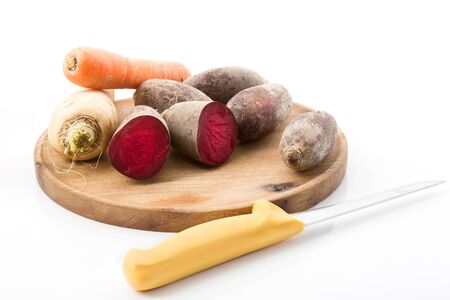 Chopping board with carrot, parsnips, parsley root, beetroot, white and red radishの写真素材