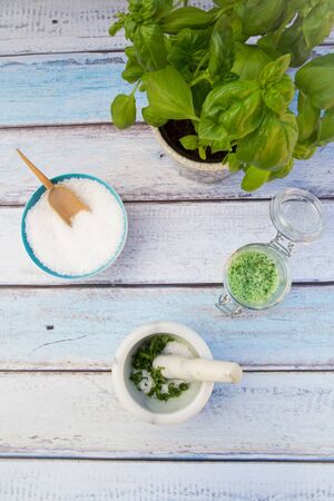 Herbal salt, salt, mortar and pestle and basil on woodの写真素材
