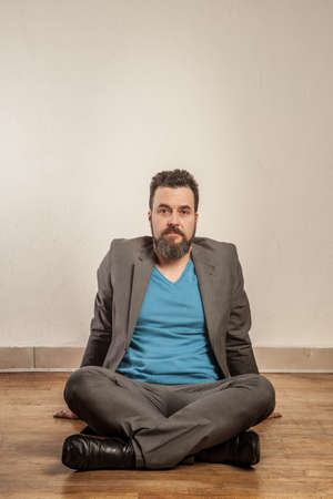 Business man with beard, sitting on wooden floorの写真素材