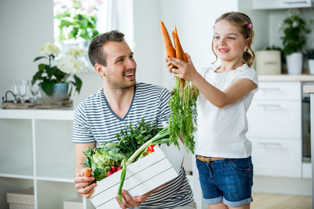 Father and daughter with vegetable box in kitchenの写真素材