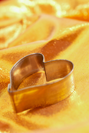 Biscuit cutter, heart-shaped, on golden clothの写真素材
