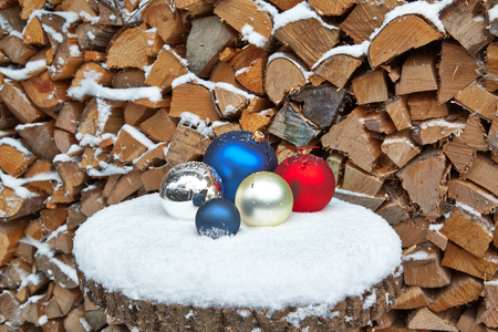 Christmas baubles on table in front of woodpileの写真素材