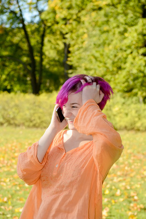 Young woman with smartphone in park, autumnの写真素材