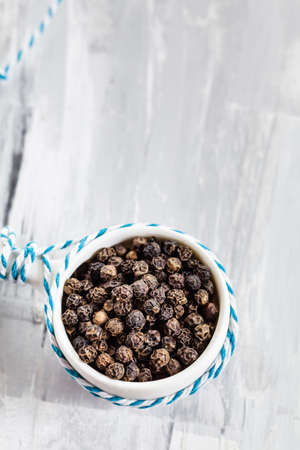Black peppercorns (Piper nigrum) in small bowlの写真素材