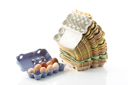 Stacked egg cartons and eggs on white background