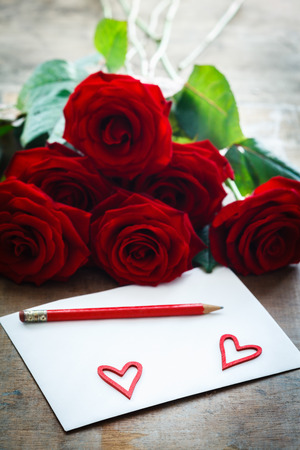 Love letter in front of bunch of red rosesの写真素材