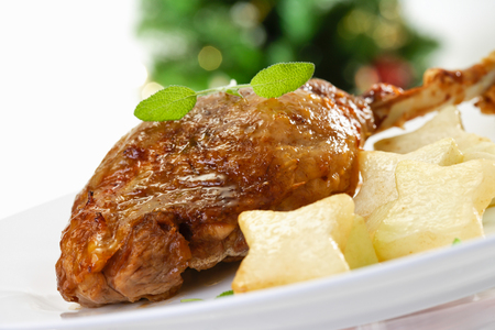 Fried goose leg with star-shaped potatoes on plateの写真素材