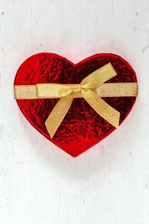 Heart shaped gift parcel with bow on woodの写真素材