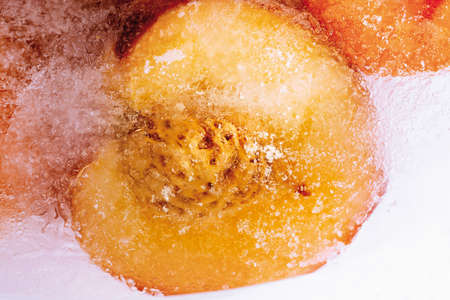 Frozen peaches in a block of ice, close-upの写真素材