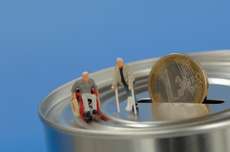 Plastic figurines, in wheelchair and with crutches on money boxの写真素材