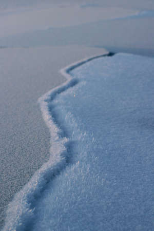 Cracked River Ice and Frost Close-up Winter Snow Surface Backgroundの写真素材