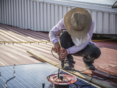 Worker install solar panel on the metal roofの写真素材