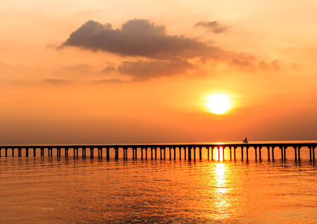 silhouette people driving bicycle on wood bridge with sunsetの写真素材