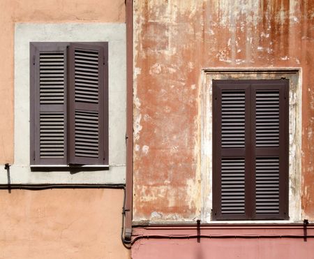 Two asymmetric windows with brown shutters - beautiful architecture detail in Rome, Italy.の写真素材