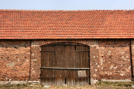 Old brick barn with wooden gate. Polish rural building. Countryside of Poland.の写真素材