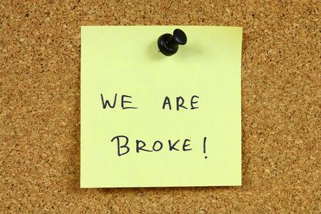 Yellow sticky note pinned to an office notice board. We are broke - bankruptcy, unemployment and financial problems message.の写真素材