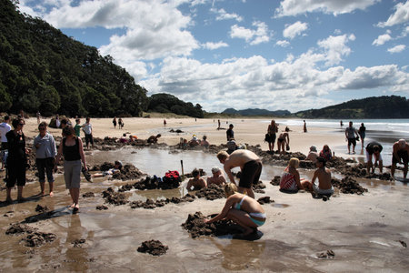 NEW ZEALAND - MARCH 11: Tourists digging their own hot springs on March 11, 2009 in Hot Water Beach, Coromandel, New Zealand. 130,000 annual visitors make it one of most popular geothermal attractions in the Waikato region.のeditorial素材