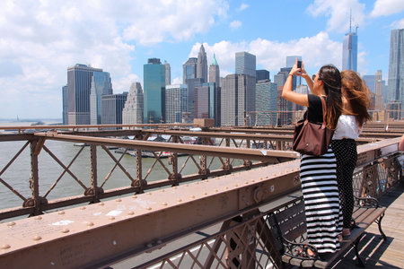 NEW YORK, USA - JULY 5, 2013: Women take photos from Brooklyn Bridge in New York. Almost 19 million people live in New York City metropolitan area.のeditorial素材