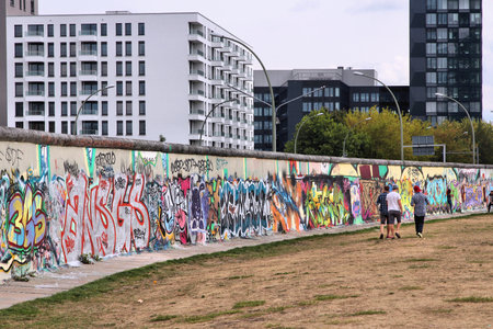BERLIN, GERMANY - AUGUST 26, 2014: People visit urban art of East Side Gallery in Berlin. Part of former Berlin Wall is covered in art by more than 100 artists since 1990.のeditorial素材