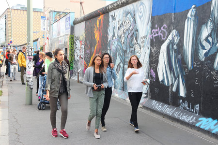 BERLIN, GERMANY - AUGUST 26, 2014: People visit urban art of East Side Gallery at public street in Berlin. Part of former Berlin Wall is covered in art by more than 100 artists since 1990.のeditorial素材