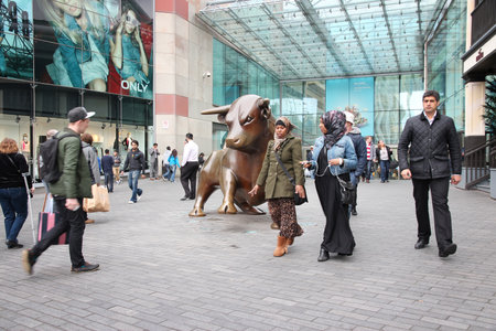 BIRMINGHAM, UK - APRIL 24, 2013: People walk past Bull sculpture at Bull Ring in Birmingham. The famous bronze sculpture was created by Laurence Broderick.のeditorial素材