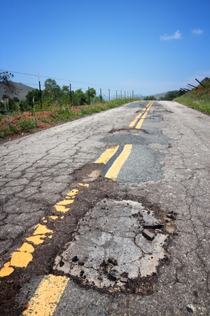 Pothole road - damaged roadway surface in California, USA.の写真素材