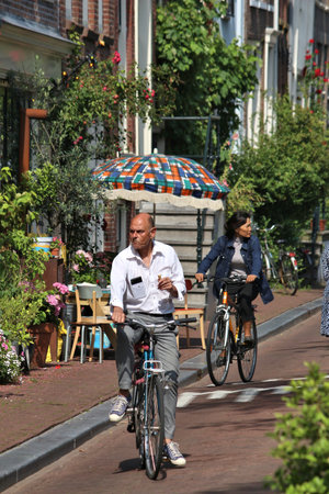 AMSTERDAM, NETHERLANDS - JULY 7, 2017: Person rides a bicycle with a child in Amsterdam, Netherlands. There are more than 13 million bikes in the Netherlands (country with 16.5 million people).のeditorial素材