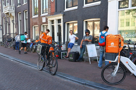 AMSTERDAM, NETHERLANDS - JULY 9, 2017: Uber Eats, Thuisbezorgd and Deliveroo food couriers wait in...