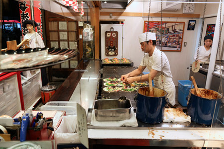 KYOTO, JAPAN - NOVEMBER 26, 2016: Restaurant chef prepares Japanese style okonomiyaki pancakes in Kyoto, Japan.のeditorial素材