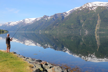 HARDANGER FIORD, NORWAY - JULY 17, 2015: Man enjoys angling at Sorfjord part of Hardanger Fiord, Norway. Foreign tourists spent some 5 million overnight stays in Norway in 2013.のeditorial素材