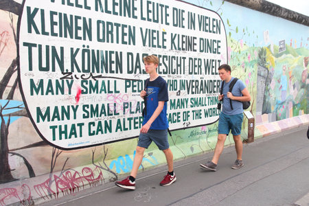 BERLIN, GERMANY - AUGUST 26, 2014: People visit urban art of East Side Gallery at public street in Berlin. Part of former Berlin Wall is covered in art by more than 100 artists since 1990.のeditorial素材