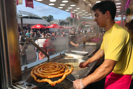 LEIRIA, PORTUGAL - MAY 22, 2018: Man prepares traditional fried dough pastry churros for the city celebration event - Days of Leiria.のeditorial素材