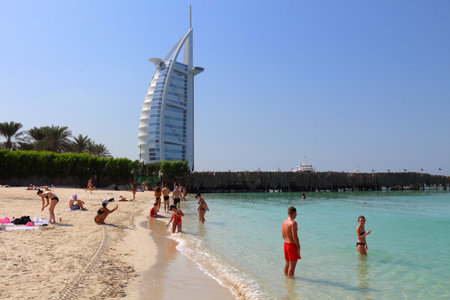 DUBAI, UAE - NOVEMBER 23, 2017: People visit the beach in Dubai, United Arab Emirates. The building in background is famous hotel, Burj Al Arab.のeditorial素材