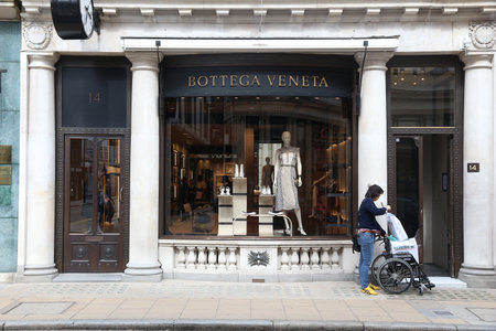 LONDON, UK - JULY 9, 2016: Shopper walks by Bottega Veneta fashion shop at Old Bond Street in London. Bond Street is a major shopping street in the West End of London.のeditorial素材