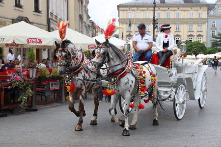 KRAKOW, POLAND - AUGUST 28, 2018: People ride a horse carriage in Krakow Market Square (Rynek), Poland. The Historic Centre of Krakow is a UNESCO World Heritage Site.のeditorial素材