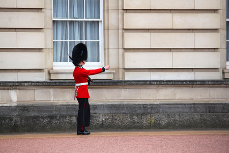 LONDON, UK - APRIL 23, 2016: Queen's Guard soldier stands in front of Buckingham Palace in London,...