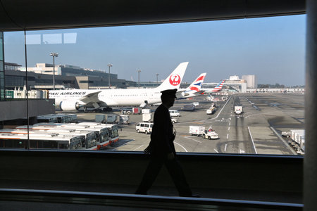 TOKYO, JAPAN - DECEMBER 5, 2016: Pilot walks by the window of Narita Airport of Tokyo, Japan. Narita International Airport is the 2nd busiest airport of Japan.のeditorial素材