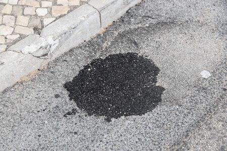 Patched pothole in local street in Albufeira, Portugal. Road maintenance concept.の写真素材