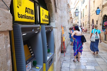 DUBROVNIK, CROATIA - JULY 26, 2019: Tourists walk by ATMs at a shopping street in Dubrovnik Old Town, a UNESCO World Heritage Site.のeditorial素材