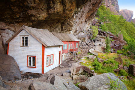 Norway landmark. Helleren old homes hidden beneath huge rock cliff in Jossingfjord.の写真素材