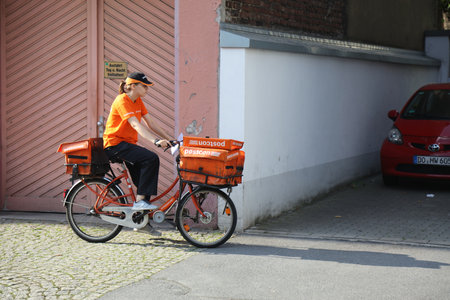 DORTMUND, GERMANY - SEPTEMBER 16, 2020: Postal worker of Postcon company delivers mail by bicycle in downtown Dortmund, Germany.のeditorial素材