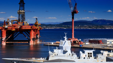 AGOTNES, NORWAY - JULY 24, 2020: Offshore drilling rig maintenance in Agotnes near Bergen, Norway. In foreground: HNoMS Helge Ingstad navy frigate waiting for being scrapped after collision.のeditorial素材