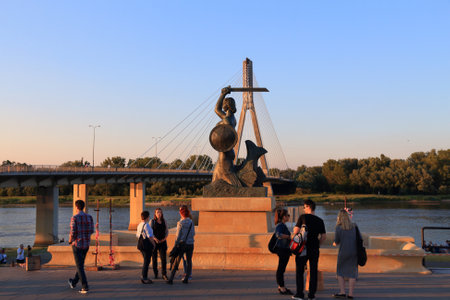 WARSAW, POLAND - JUNE 18, 2016: People visit Mermaid (Syrenka) statue by Vistula River in Warsaw, Poland. Mermaid is an important symbol of the city.のeditorial素材