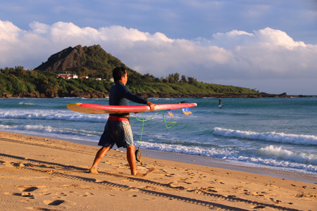KENTING, TAIWAN - NOVEMBER 28, 2018: Surfer approaches the waves in Kenting Beach, Taiwan. Kenting National Park is a popular taiwanese beach destination.のeditorial素材