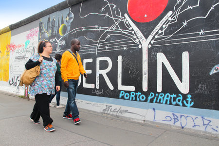 BERLIN, GERMANY - AUGUST 26, 2014: People walk a public sidewalk along the Berlin Wall (Berliner Mauer). Iconic iron curtain border divided Berlin in years 1961-1989.のeditorial素材