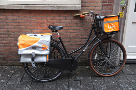 AMSTERDAM, NETHERLANDS - DECEMBER 6, 2017: Mailman bicycle parked in Amsterdam. Mail delivery by Post NL national postal service.のeditorial素材