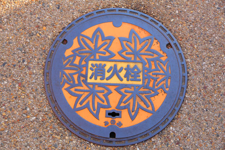 MINOO, JAPAN - NOVEMBER 22, 2016: Ornamented manhole cover featuring autumn leaves decor in Minoo, Osaka. Japan frequently has beautiful decorative sewer covers.のeditorial素材