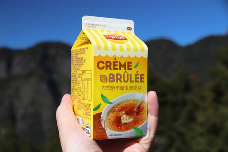 ALISHAN, TAIWAN - DECEMBER 1, 2018: Customer hand holding Lipton Creme Brulee Milk Tea beverage in Taiwan. Lipton brand is part of Unilever group.のeditorial素材