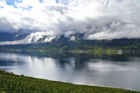 Norway landscape - Hardanger Fiord with rays of sunshine. Farms in municipality of Odda.