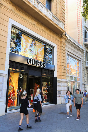 BARCELONA, SPAIN - OCTOBER 7, 2021: People walk by Guess brand fashion store at Passeig de Gracia...